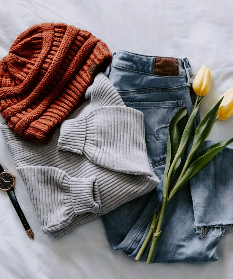 Tenue posée à plat : pull gris, jean, bonnet, montre et deux tulipes